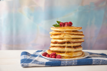 pancakes with raspberries and honey lie on a plate on a blue napkin