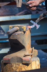 blacksmith performs the forging of hot glowing metal on the anvil