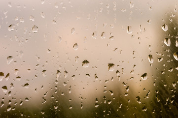 raindrops on window glass on background of cloudy sky