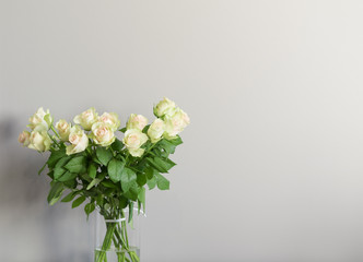 Beautiful bouquet of bright white roses. Fresh white roses in a vase. Bouquet of white roses on gray background. Fresh bouquet of flowers