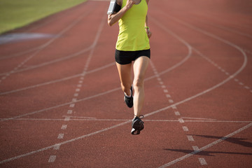 Fototapeta premium Fitness sportswoman running on stadium race tracks