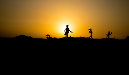 Fototapeta na wymiar Cowboy concept. Silhouette of Cowboys at sunset time. Cowboys silhouettes on a hill with horses.