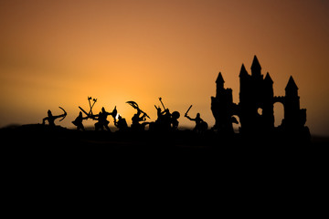 Fototapeta na wymiar Medieval battle scene with cavalry and infantry. Silhouettes of figures as separate objects, fight between warriors on sunset foggy background.