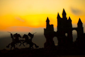 Medieval battle scene with cavalry and infantry. Silhouettes of figures as separate objects, fight between warriors on dark toned foggy background with old gothic castle