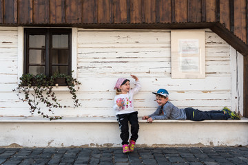 Girl and boy are resting in front of beautiful old building/house in Frydlant, Czech Republic.