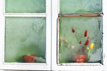 old frozen window with white wooden frame from outside 