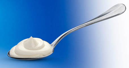 Sour cream in spoon isolated on blue background