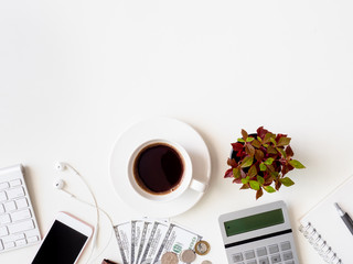 top view of accounting concept with keyboard, smartphone, notebook, coffee cup, calculator and money on white table background with copyspace.