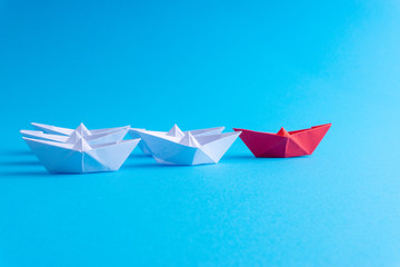White and red paper ship in one direction on blue background. Business for innovative solution concept with selective focus