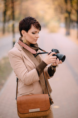 young female with camera in hand on background of autumn city