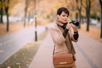 young female with camera in hand on background of autumn city