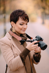young female with camera in hand on background of autumn city