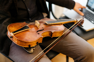 violin and bow lie on the lap of a male violinist, cropped image