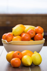 diverse fruits, all citrus, in front of a fruit bowl filled with citrus and bananas
