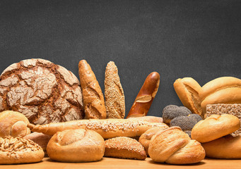 Reiche Auswahl an Brot und Gebäcksortiment mit Tafel im Hintergrund für eigene Botschaft - obrazy, fototapety, plakaty