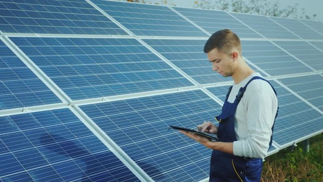 The engineer uses the tablet on the background of solar panels. Alternative energy and solar energy