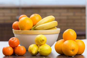 three heaps separating citrus, oranges, tangerines and lemons, behind a full fruit bowl