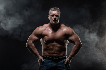 Obraz na płótnie Canvas Powerful muscular bodybuilder posing on a black background. concept of strength and health