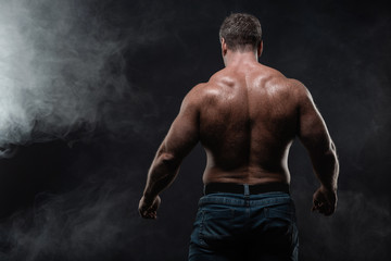 Fototapeta na wymiar muscular man posing on black background showing his back