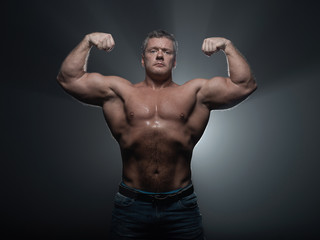 Fototapeta na wymiar Powerful muscular bodybuilder posing on a black background. concept of strength and health