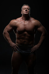 Obraz na płótnie Canvas Powerful muscular bodybuilder posing on a black background. concept of strength and health