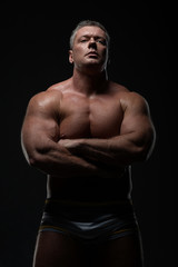 Fototapeta na wymiar Powerful muscular bodybuilder posing on a black background. concept of strength and health