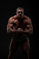 Fototapeta na wymiar powerful muscular man shows biceps on a black background. Strength and fitness concept