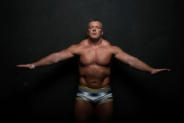 Obraz premium muscular man shows off his body near black grunge wall