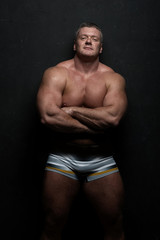 Fototapeta premium muscular man shows off his body near black grunge wall