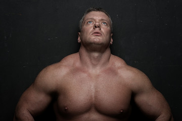 Fototapeta premium muscular man shows off his body near black grunge wall