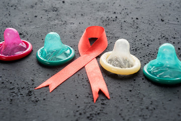 Red ribbon with four condoms on the table