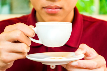 Young brunette is drinking morning coffee in the garden happily.