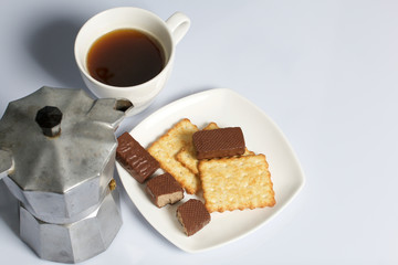 Coffee in a geyser coffee maker cookie and candy on a saucer stand on a wooden box. On a white background.