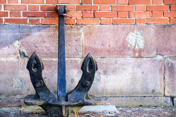 Ancient anchor stands on the ground leaning against the wall © Андрей Михайлов