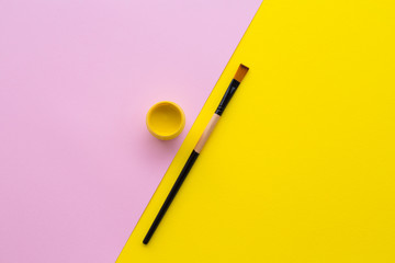 Yellow paint, brush, pink and yellow background.