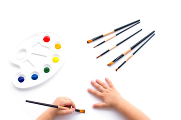 Paints, brushes and hands of the child.