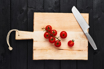 Top view of chopping board with stainless steel vegetable knife and tomato on black wooden...