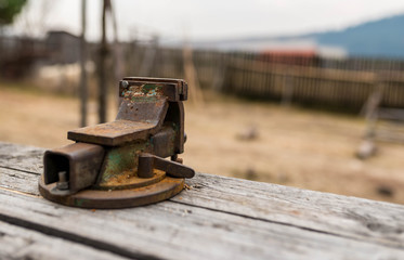 Old rusty metal vise on pine table close up shot. 