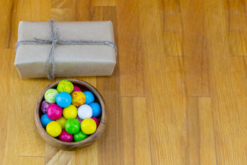 base festive rectangular box in brown kraft paper with natural rope and bowl of candy dragees on a...