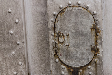 iron hatch oval technical hole on background gray surface rivets weather-beaten rusty base industrial design