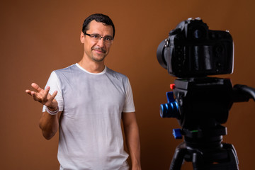 Portrait of photographer man vlogging against brown background