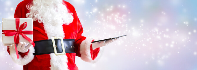 Santa holding a tablet computer on a shiny light background