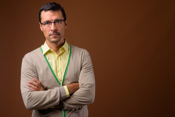 Portrait of handsome man with arms crossed against brown background