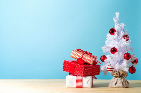 Small white christmas tree with presents on a blue background