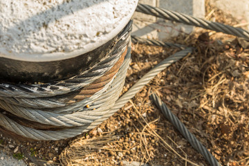 stone pedestal coiled iron cable mooring powerful fixation ship on sand background close-up copy space