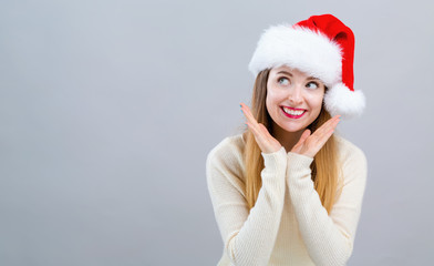 Happy woman with a Santa hat on a gray background
