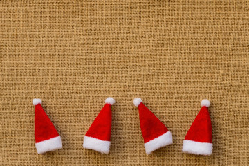 Bordüre aus 4 Weihnachtsmützen auf Hintergrund aus Jute