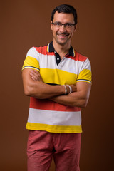 Handsome man smiling against brown background with arms crossed