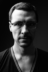 Black and white studio portrait of man wearing eyeglasses