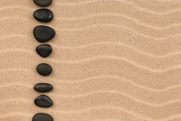 Fototapeta na wymiar Line made of black stones among sand dunes.